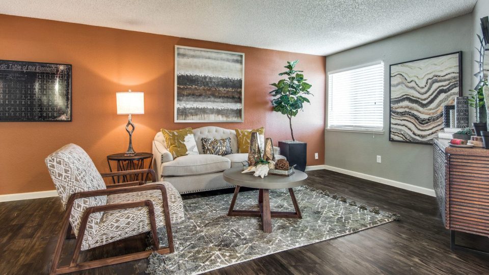 a living room with orange walls and wood floors at The  Mark at 2600