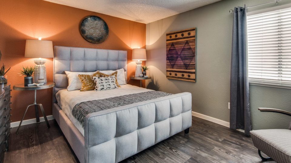 a bedroom with orange walls and a white bed at The Mark at 2600