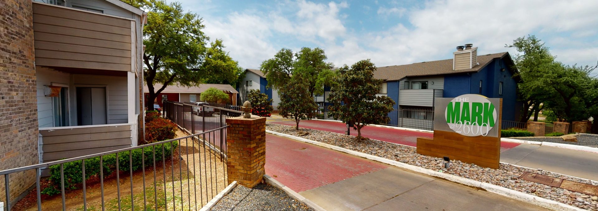 the entrance to a residential area with a green fence at The  Mark at 2600